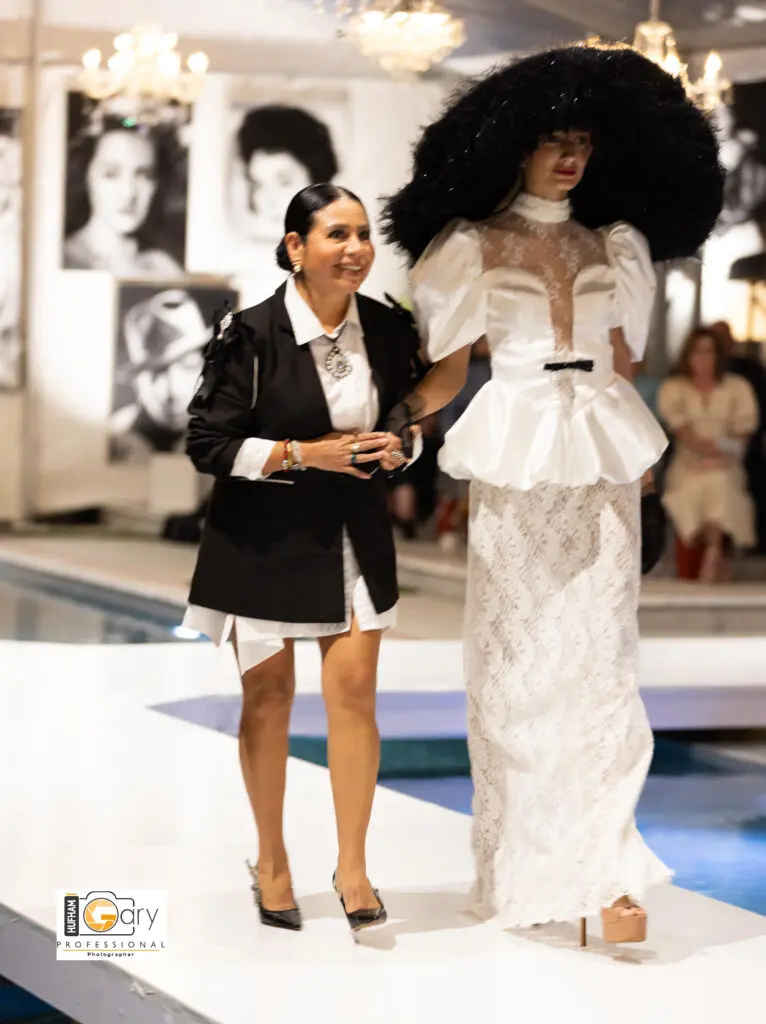 Los Angeles-based designer  Maribel Julcahuanca walks the runway with one of her models at "Fashion Woodlands" at the home of Theresa Roemer.