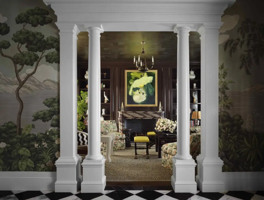 A view into the living room with leopard-print Stark carpeting, slipper chairs in Rose Cumming chintz, Corri-Lynn Tetz painting. Farrow & Ball Mahogany on walls. (Photo by Douglas Friedman)