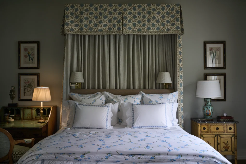 A guest bedroom with hand-painted antique furniture and framed botanicals from Wagner’s grandmother. D. Porthault bedding; canopy fabric from George 
Cameron Nash. (Photo by Pär Bengtsson)