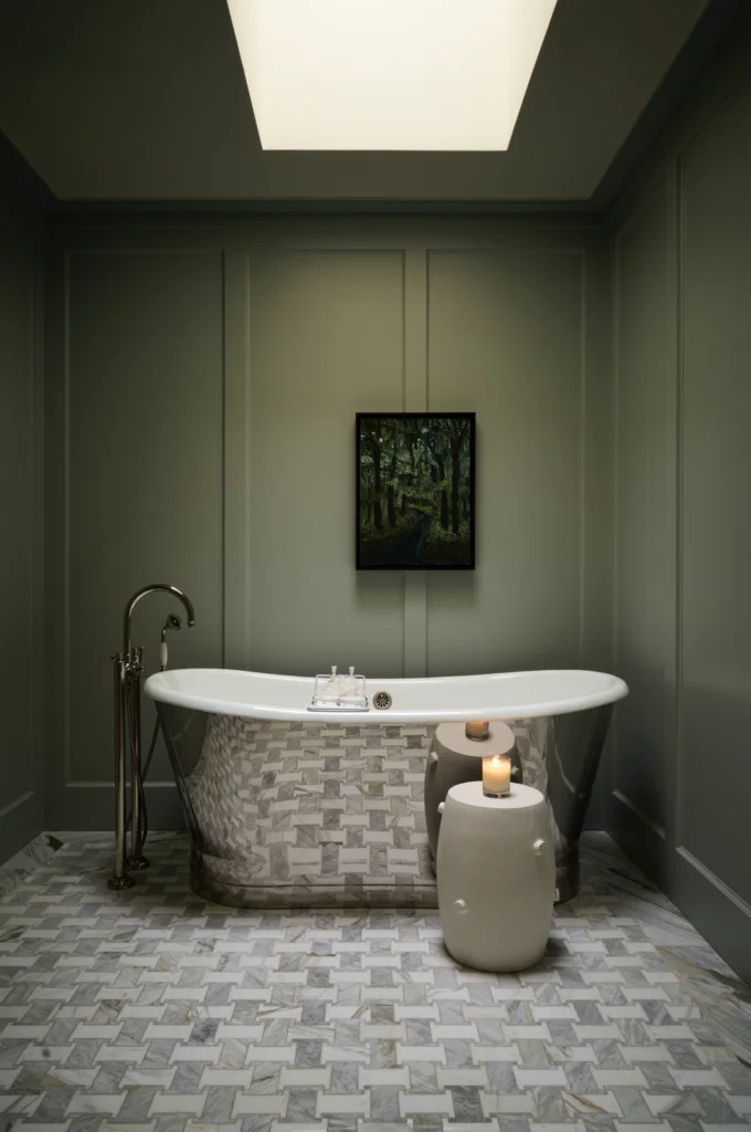 In the primary bath, Slik Portfolio cast-iron mirror tub. Waterworks plumbing and floor tiles. Farrow & Ball Light Blue on walls. Christopher Spitzmiller ceramic stool. Painting, unknown artist from Niven Morgan’s collection of Louisiana Outsider artists. (Photo by Pär Bengtsson)