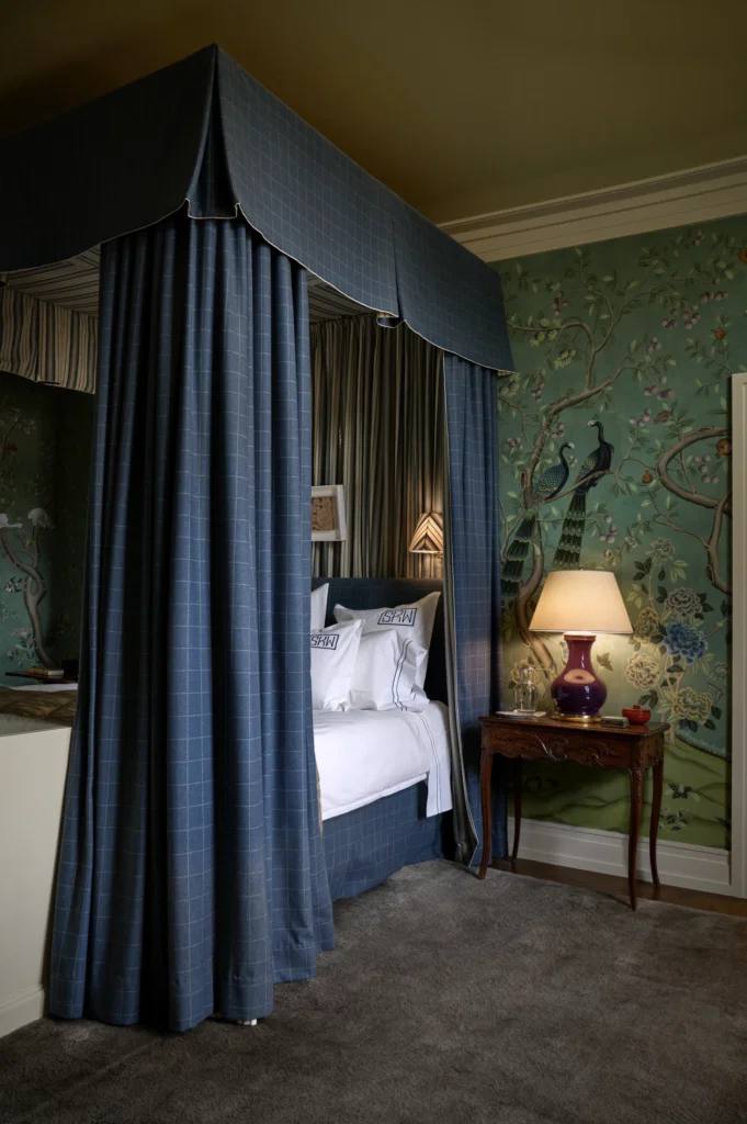 The primary bedroom wallpaper is de Gournay. Canopy in Lee Jofa windowpane pattern fabric and 
Rose Tarlow stripe fabric. 
Christopher Spitzmiller lamp.  (Photo by Pär Bengtsson)