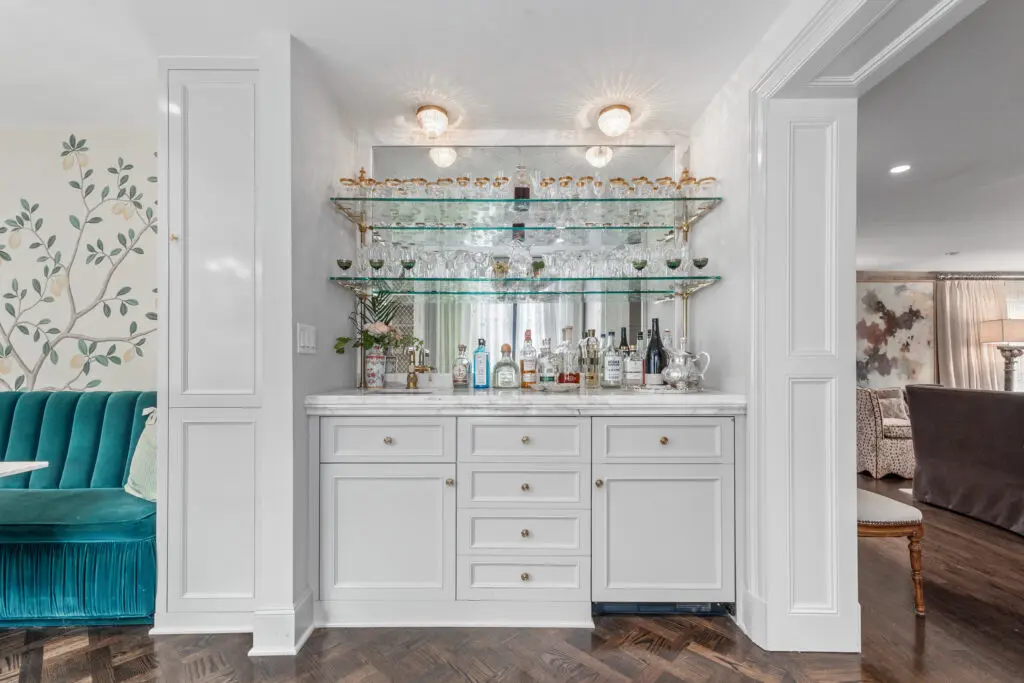 A mirrored bar with glass shelving and brass accents offers a glamorous spot for cocktail hour.  (Photo by Freeze Media FW)