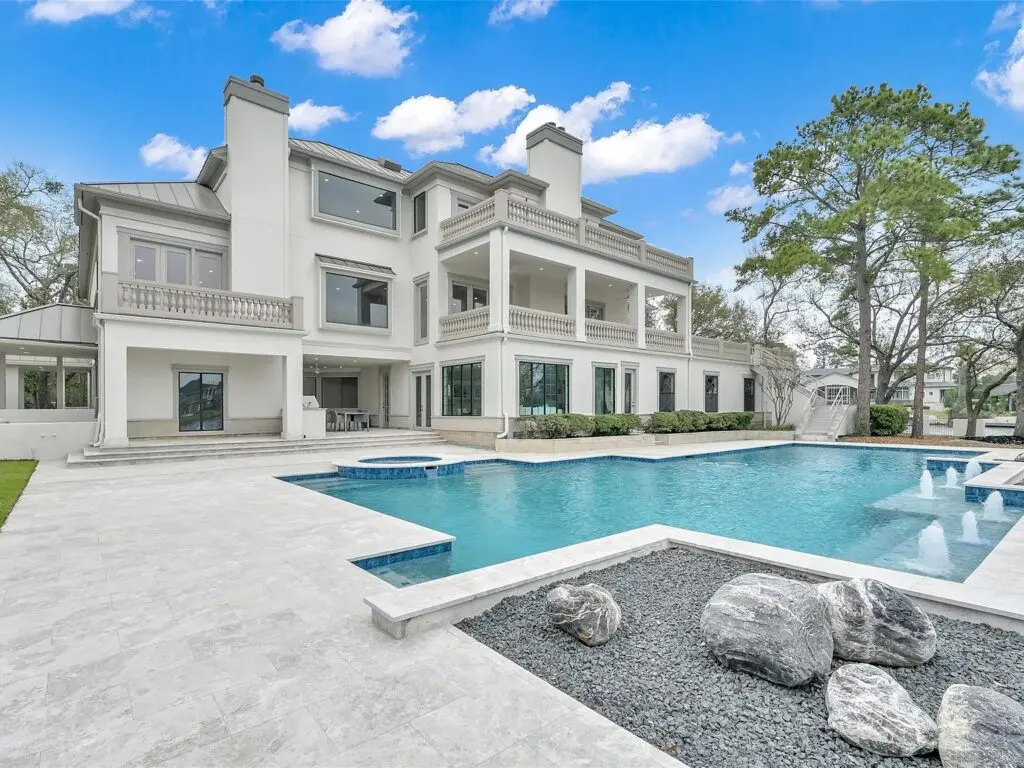 The three story home has a pool and hot tub overlooking Lake Woodlands.