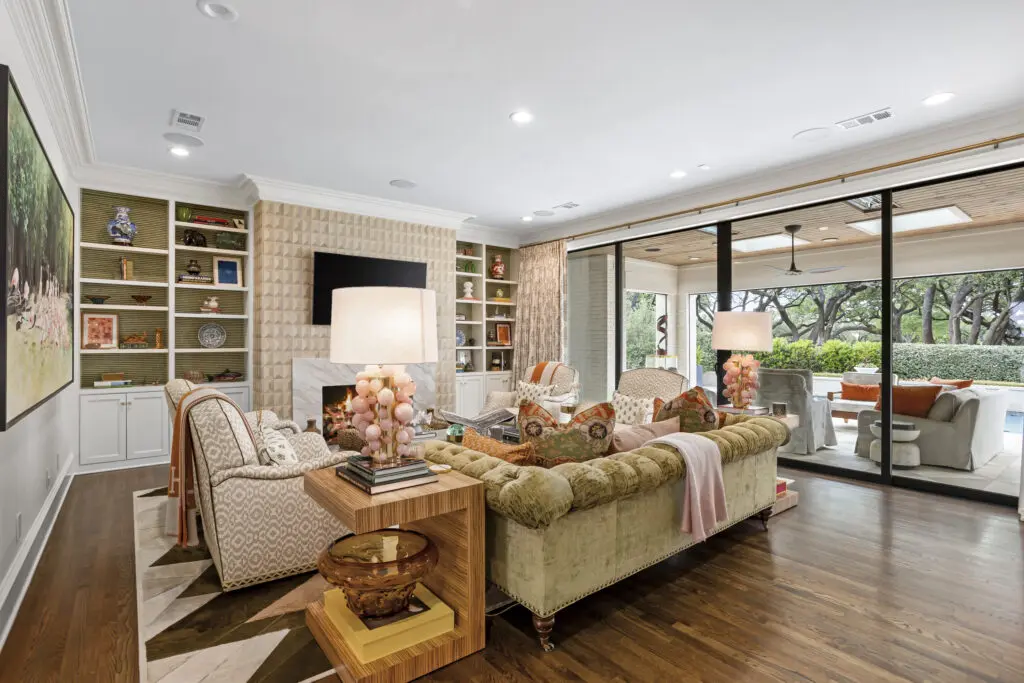 The main living room at 1128 Shady Oaks Lane opens directly to the pool and patio, combining plush seating, custom millwork, and a soft blend of color and texture curated by Maven Interiors. (Freeze Media)