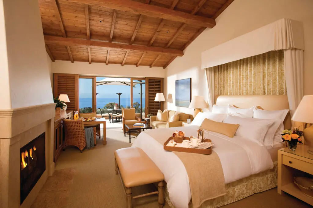 Well-appointed bungalow rooms include a wood beam ceiling, a fireplace framed by Italian limestone, and a deep soaking tub, as well as a private terrace. (Photo by The Resort at Pelican Hill)