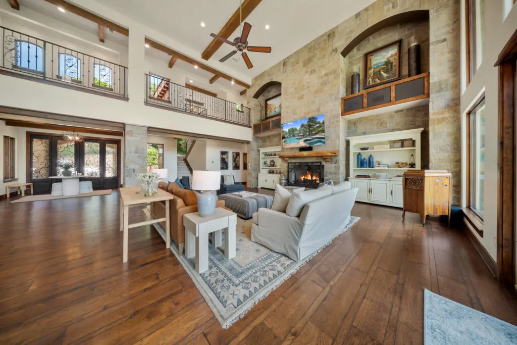 Inside the great room, a soaring stone fireplace, vaulted ceilings, and exposed beams anchor the open-concept layout.  (Photo by The Ashton Agency)