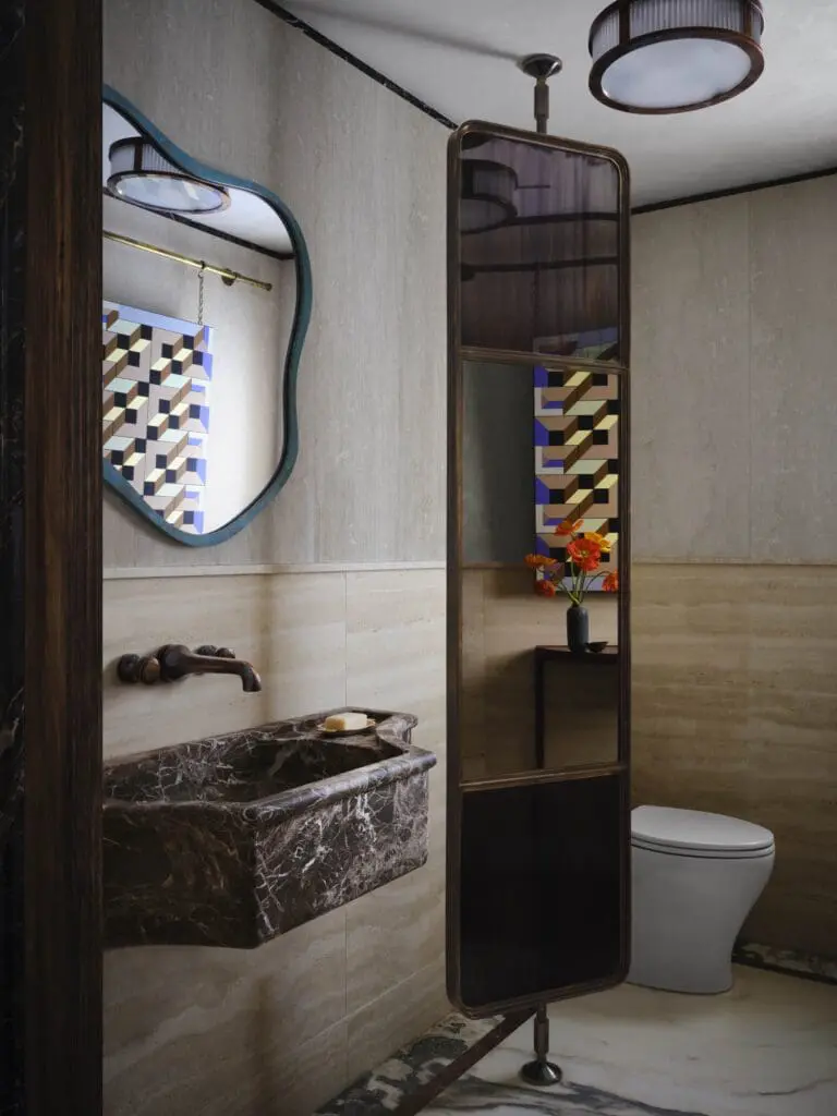 A powder bathroom in the studio with custom stone sink designed by Doniphan Moore in carved and sandblasted rosso levanto marble. Stone walls by Marble Buro. (Photo by Douglas Friedman)