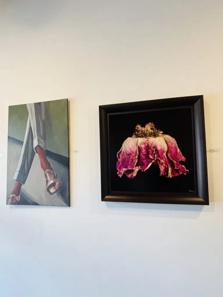 An installation view of Archway Gallery's 17th Annual Juried Exhibition. Pictured Left to Right: Grant Pilon's painting "Conspicuous Socks" and Patti Gary's "Rose Couture." (Photo by Ericka Schiche)