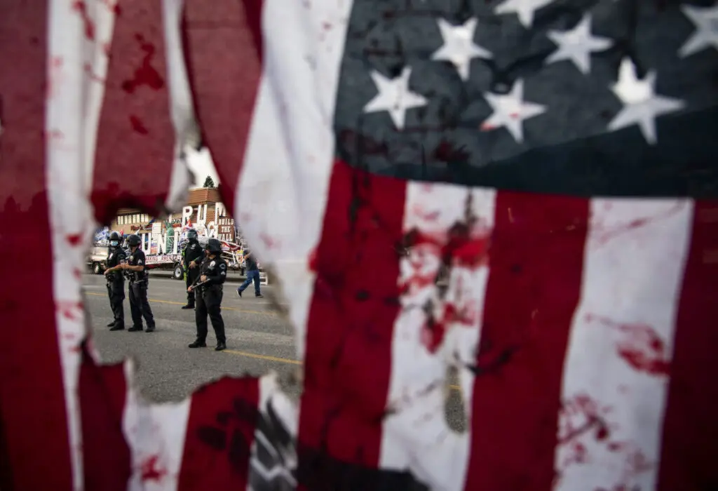 Raquel Natalicchio photographed this 2020 work showing the LAPD through a ripped American flag waved by a protestor in Los Angeles during a demonstration after the killing of George Floyd. (Photo courtesy Houston Center for Photography)