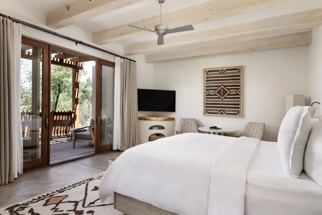 Beyond the stucco exterior, tranquil guest rooms feature wood beams, a kiva fireplace, a courtyard with an outdoor fireplace, and a dreamy Southwestern color palette. (Photo by Four Seasons Resort Rancho Encantado Santa Fe)
