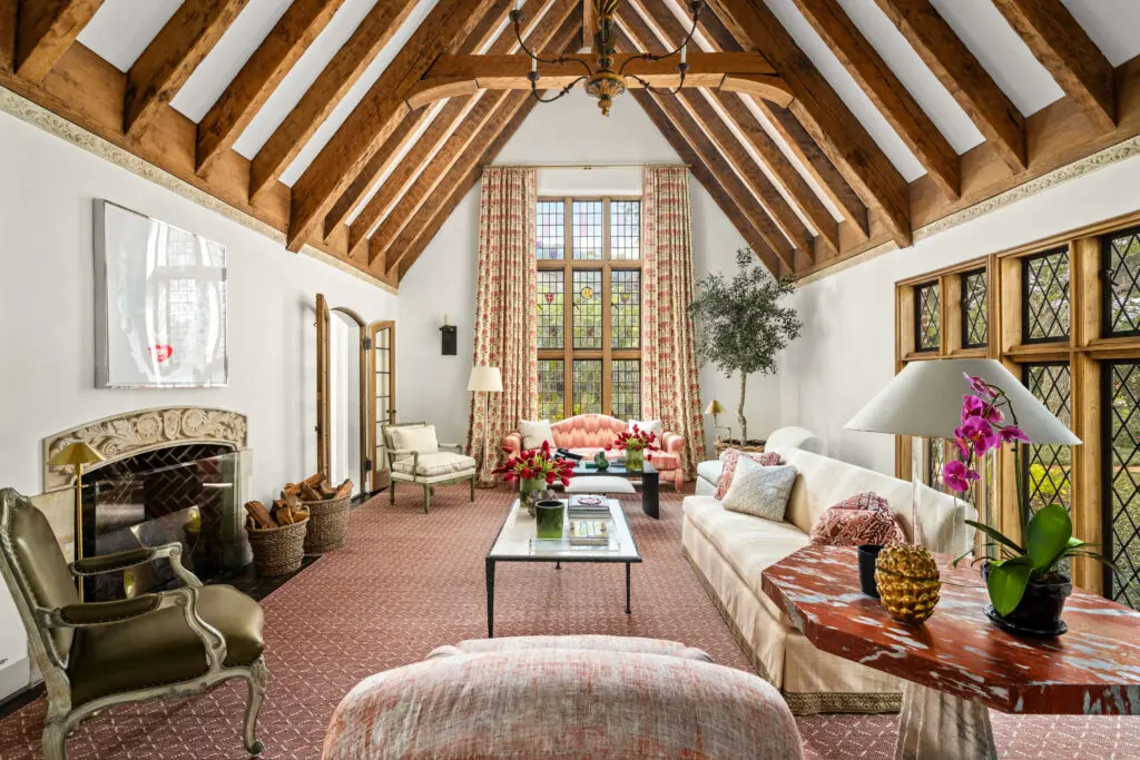 The soaring living room is anchored by exposed beams and striking windows of leaded glass. (Photo by Sonya Bertolino / Compass)