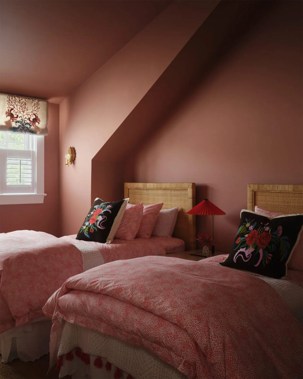 A guest bedroom is color-drenched in a Benjamin Moore salmon hue, with Schumacher embroidered and appliqué shades and custom
bedding (Photo by Douglas Friedman)