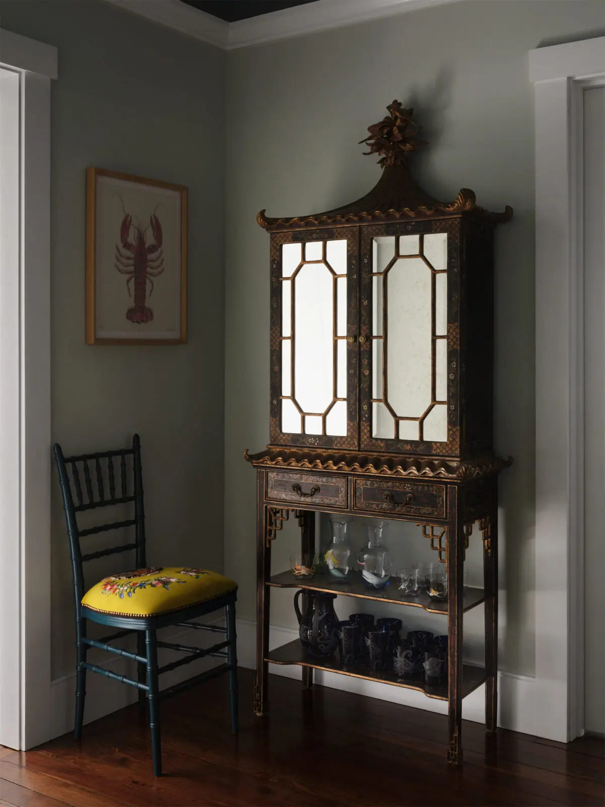 In a hallway off the living room, an English Chippendale-style chinoiserie cabinet from Legacy Antiques holds barware. Gucci chair. Lobster artwork found on Martha’s Vineyard. (Photo by Douglas Friedman)