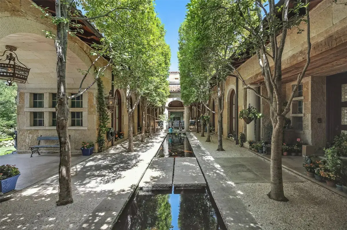A tree-lined courtyard centered on a long reflecting pool showcases 6236 Indian Creek Drive's Mediterranean-inspired design. (Courtesy)