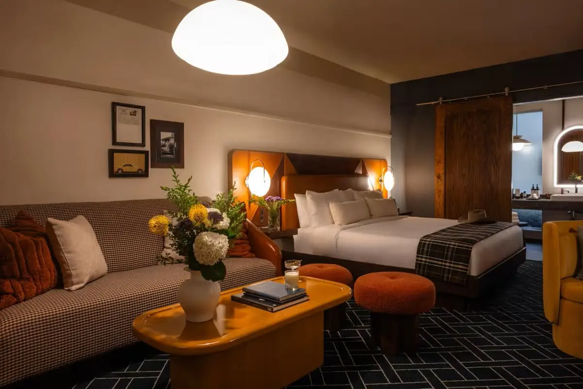 Guest suites blend olive green, warm wood tones, leather accents, and geometric flooring with mid-century-inspired furnishings. (Courtesy)