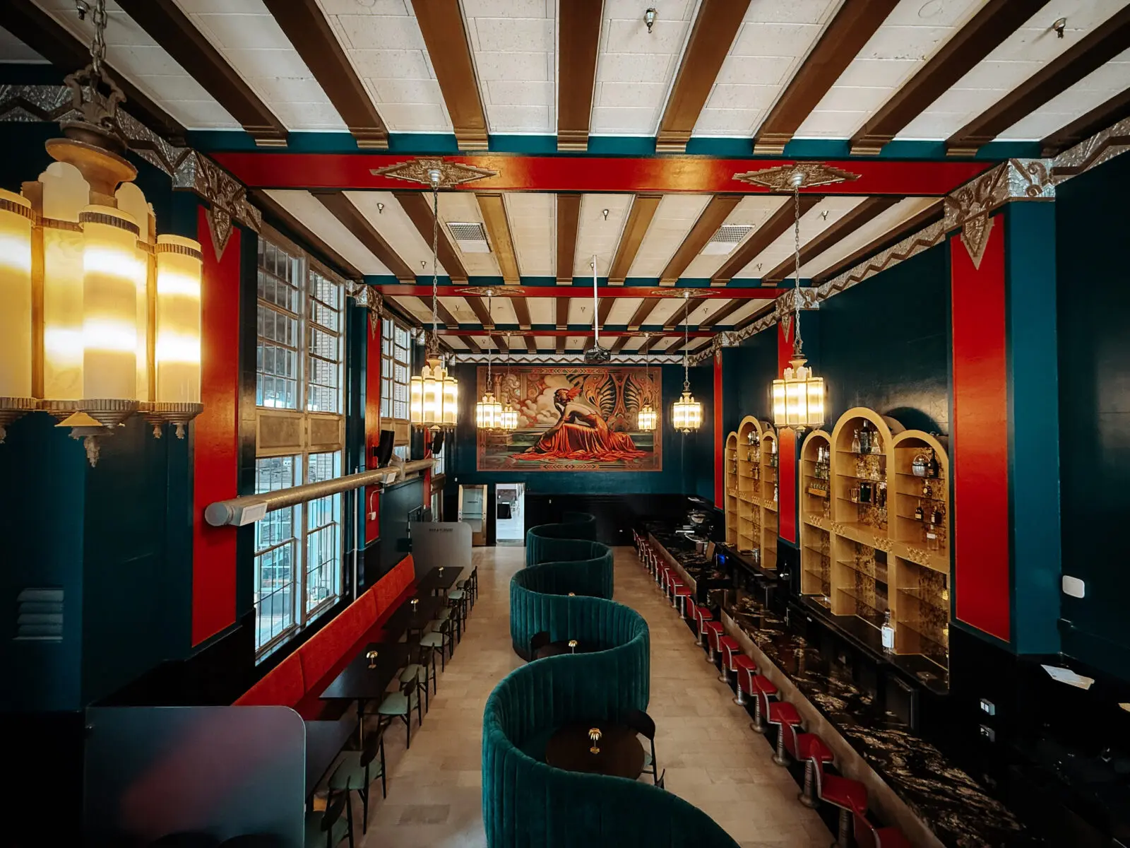 Deep teal velvet banquettes and a dramatic ruby-red mural give the dining room a lavish, almost fantastical Art Deco aesthetic. (Photo by David Witherspoon)