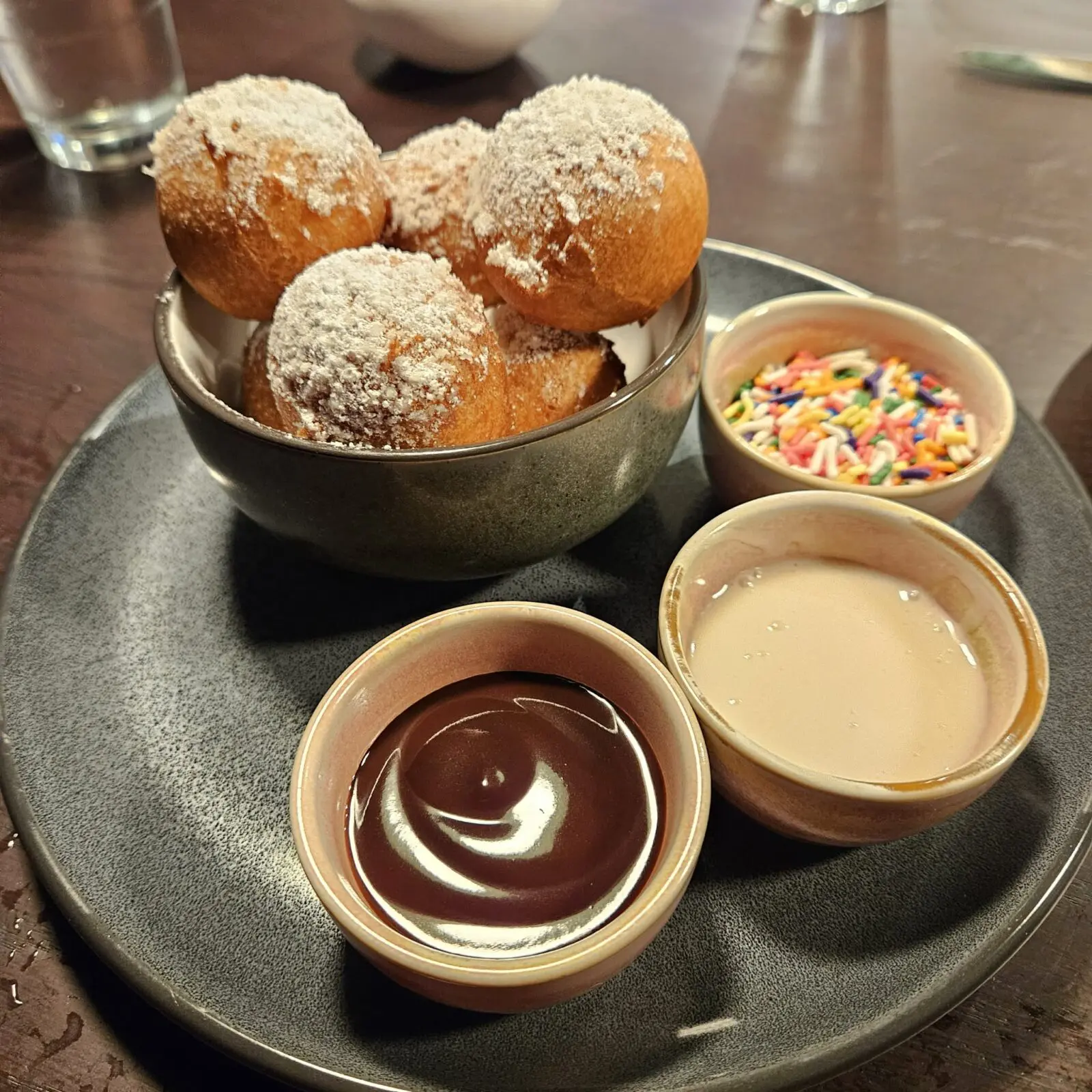 Donut holes are served with chocolate sauce, frosting, and sprinkles for a playful, interactive dessert. (Courtesy)