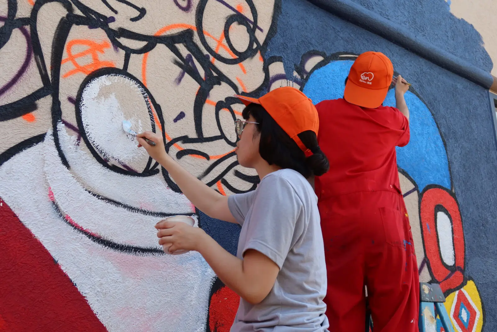 Artist Ami Liu working on the "Painted Bridges" mural (Photo courtesy of EpNex)