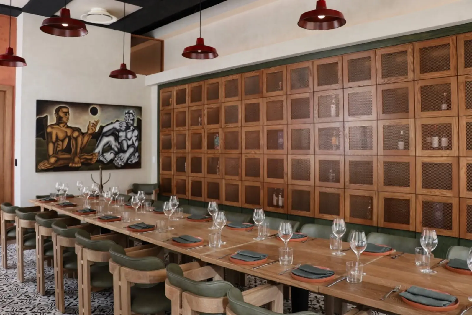 Almacén el Gallo offers a private dining room for up to 30 guests, featuring a long communal table, olive-green seating, patterned tile floors, red pendant lights, and contemporary Mexican artwork. (Photograph by Almacen el Gallo)

