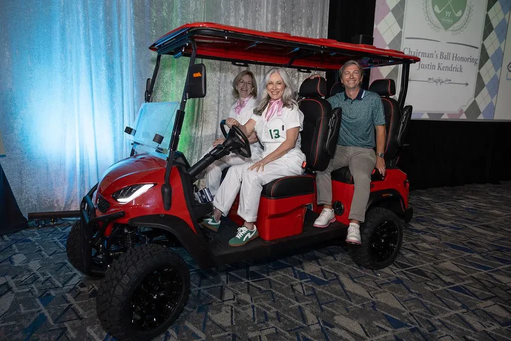 Event chairs Stacie Coleman and Laura Landsbaum escorted honoree Justin Kendrick to the stage in a golf cart. (Photo by Visibly Illustrated Photography)