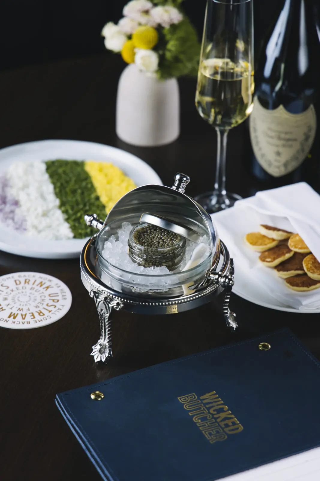 Wicked Butcher serves Gold Ossetra Sturgeon caviar from Regalis Foods with classic accompaniments including crème fraîche, warm blinis, egg, red onion, and chives. (Photo courtesy Wicked Butcher)