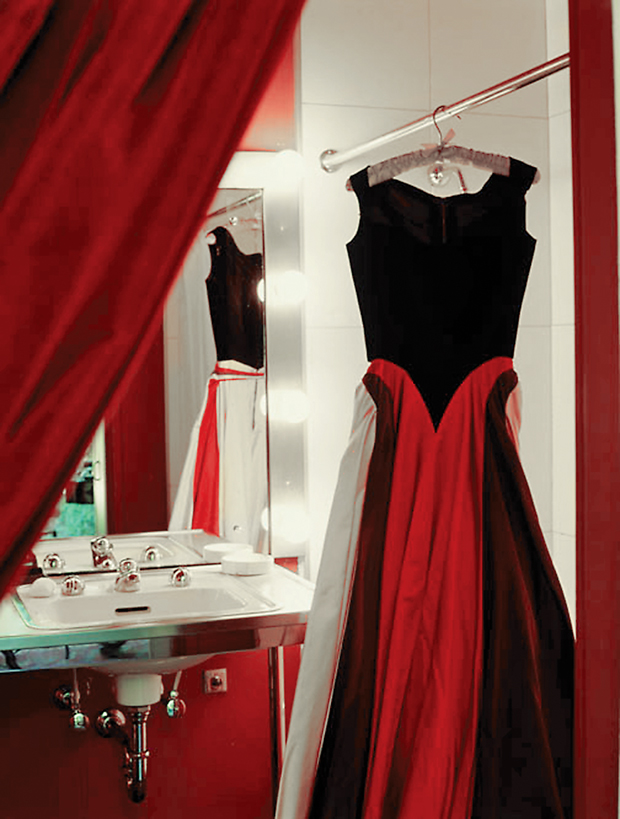 The red velvet bustle-like
curtain between Dominique’s dressing room and bath, echoed in her gown hanging on the shower curtain rod, where she often steamed garments.
