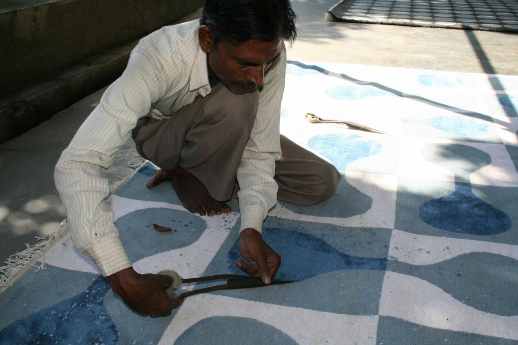 Hand scissoring a finished carpet, the final step before the carpet is ready to ship.