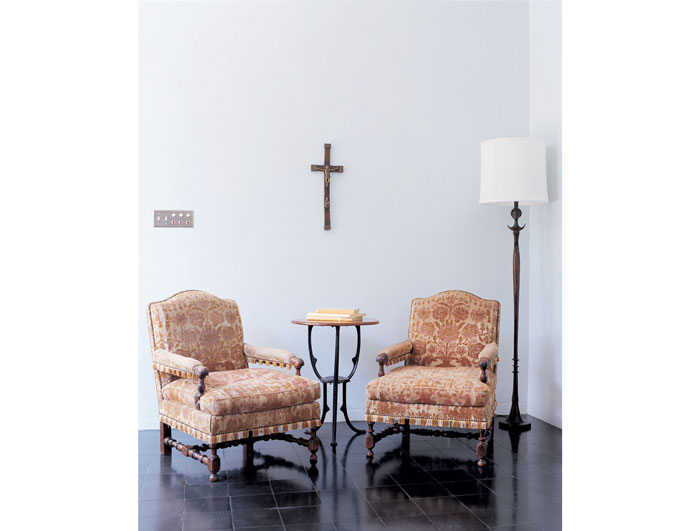 A pair of timeworn 18th-century Italian walnut open arm chairs, covered in cut velvet, flanks a round pedestal table 