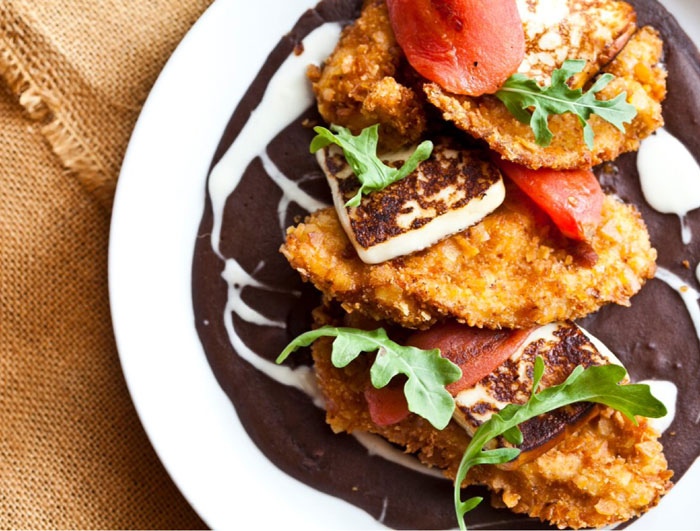 Pollo Encamisado at America's & Churrascos. Plantain crusted chicken over spicy smoked black bean sauce, seared panela cheese, roasted tomato & crema nica. 
