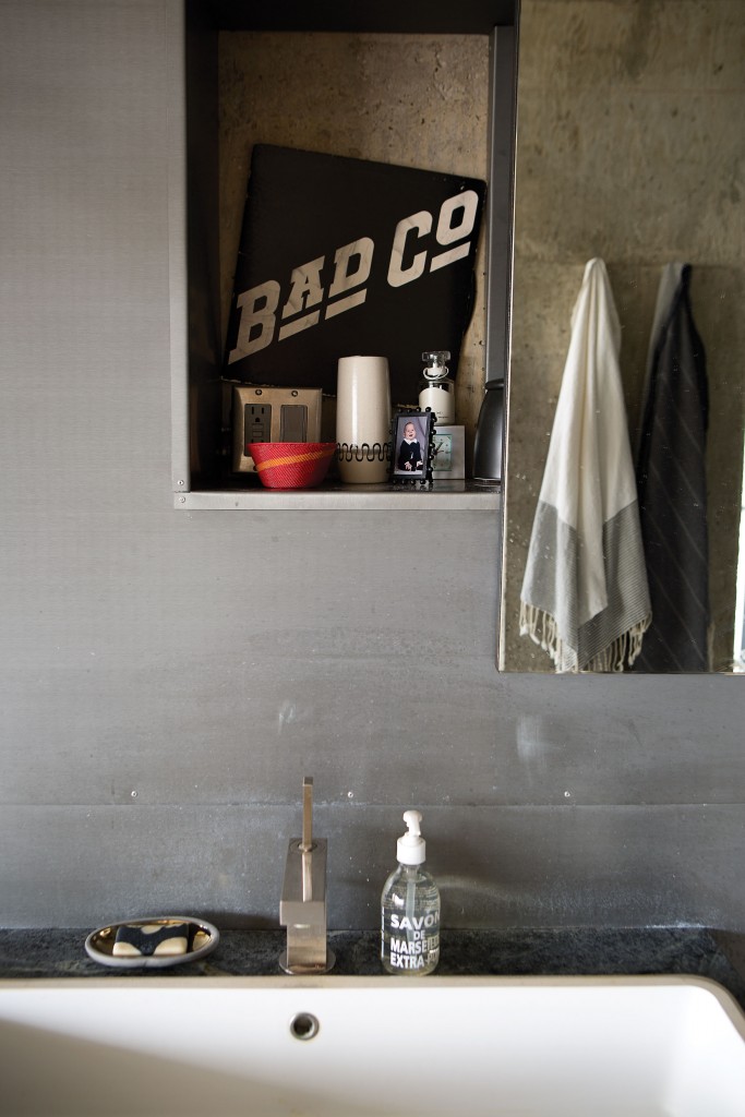 In the bath, La Cava’s Aqua Grande sink has been left unfinished. Reflected in the mirror is a vintage Bad Company album cover.