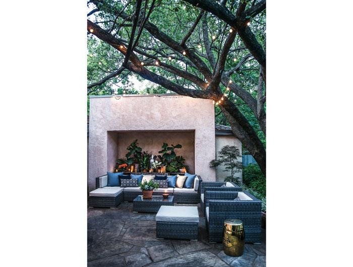 In the garden, a massive alcove holds a table of plants and candles. The outdoor furniture is from overstock.com.
