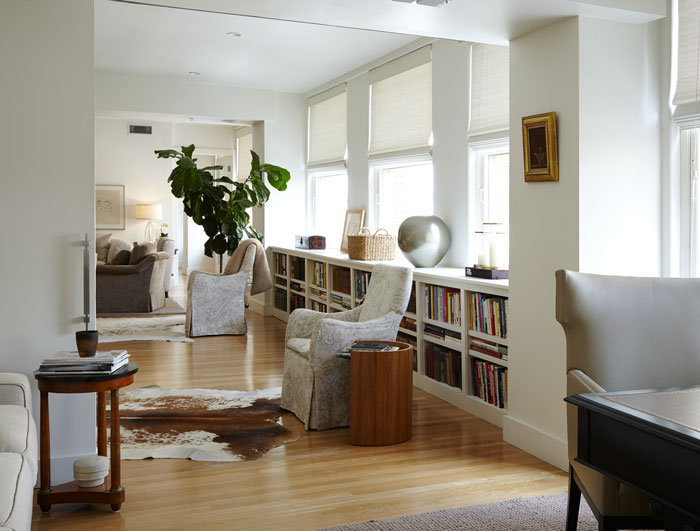 A view from the study into the living area includes the couple’s collection of books, a pair of armchairs upholstered in Peacock Alley linen fabric, and a walnut side table purchased at the Peacock Alley showroom. The floors throughout are white pine.