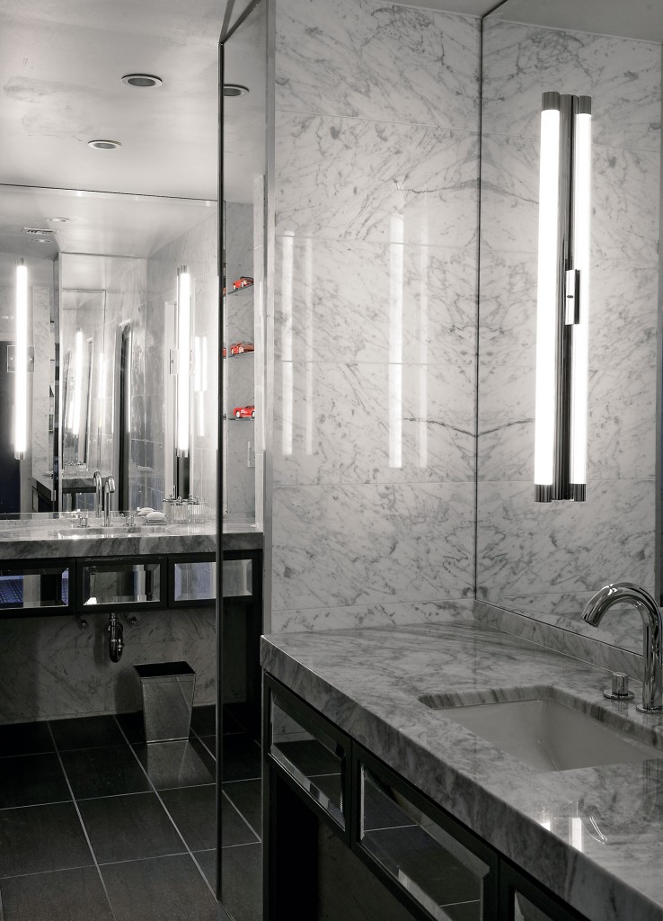 The stark master bath incorporates mirror and veined Carrara marble.