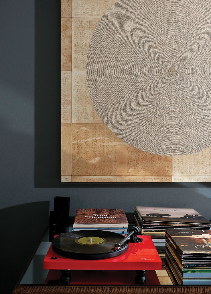 Eschewing contemporary
modes of music listening, a turntable and LPs top a table in the master bedroom. A piece by Louisiana artist Mary Ellen Leger is a study of compulsive perfection, composed by positioning words cut from dictionary
pages in a circle on top
of glazed Braille text.