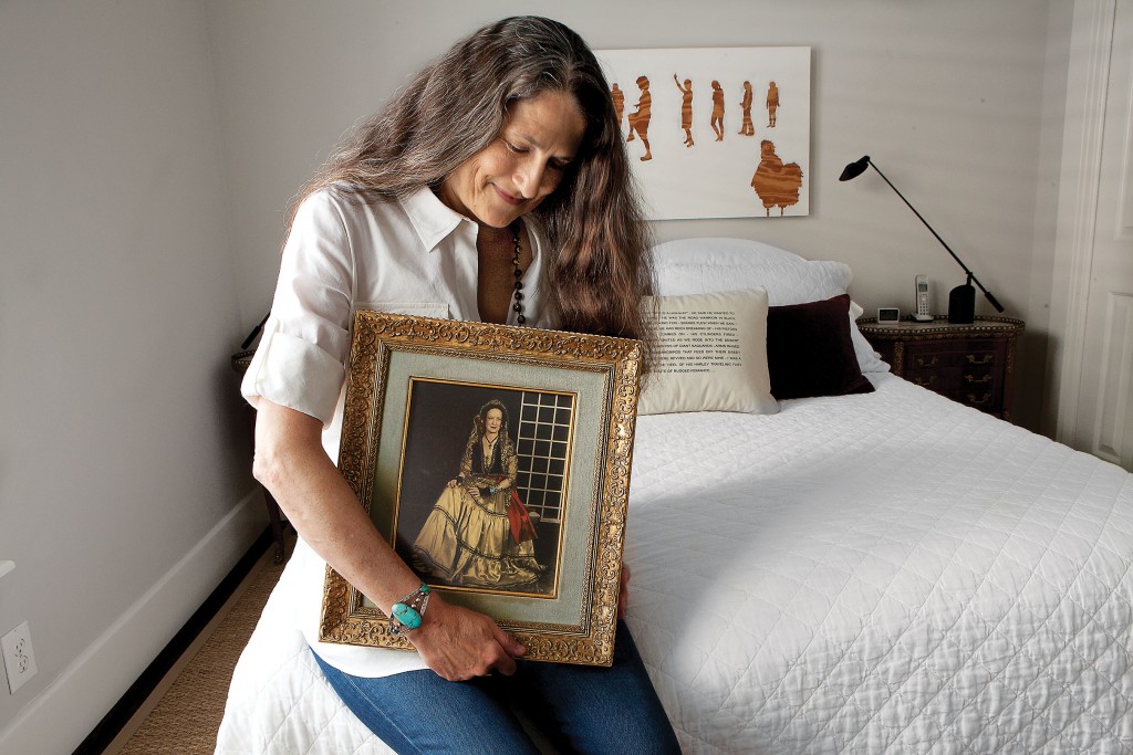 The artist in her bedroom, with a portrait of her paternal grandmother, who was from Cuero, Texas, dressed as a Spanish contessa. Over the bed, a work by Houston painter Kristen Cliburn.