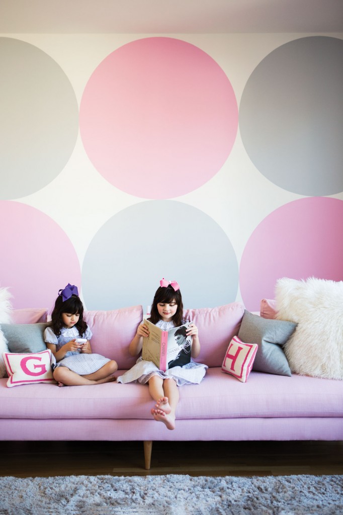 From left, GG and Hadleigh in their playroom. Custom pink sofa designed by Gable. G and H initial pillows from Jonathan Adler. Hand-painted polka dots on wall.