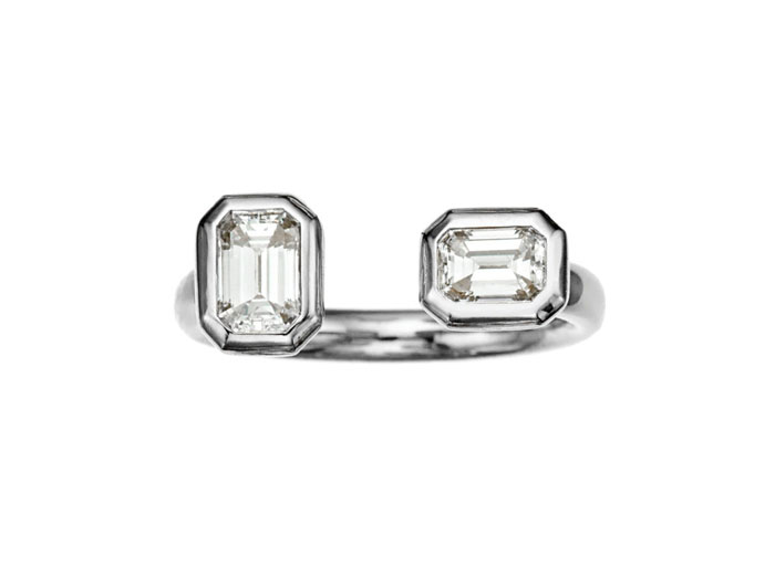 This unique ring is fashioned in 18-karat white gold and features two emerald-cut diamonds. 
