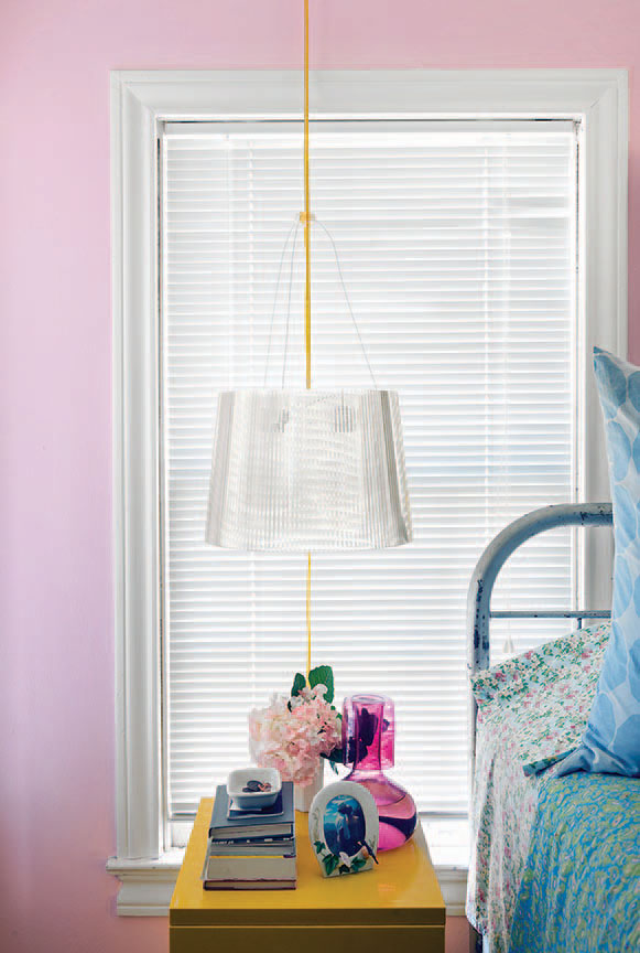 In the guest room, a Kartell pendant light hangs above a vintage bedside table from The Guild Shop. Ralph Lauren linens dress the iron bed inherited from Sensabaugh’s grandparents.