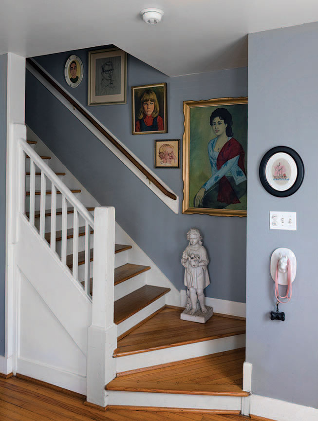 The couple’s portrait collection fills the stairwell. Antique marble garden statue. Embroidered artwork by Sensabaugh. Ceramic dog head serves as leash holder.