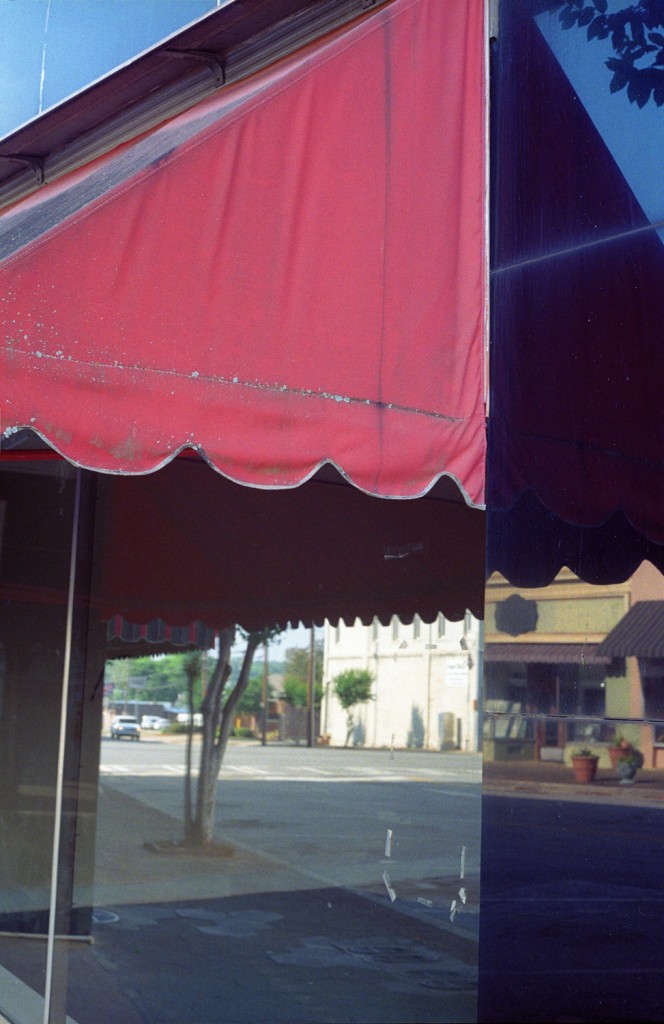 Chris Akin's "Downtown Americus, Sumter County, Georgia," 2014. The image depicts a split view of the old and new south in the window of a Best Western Inn.