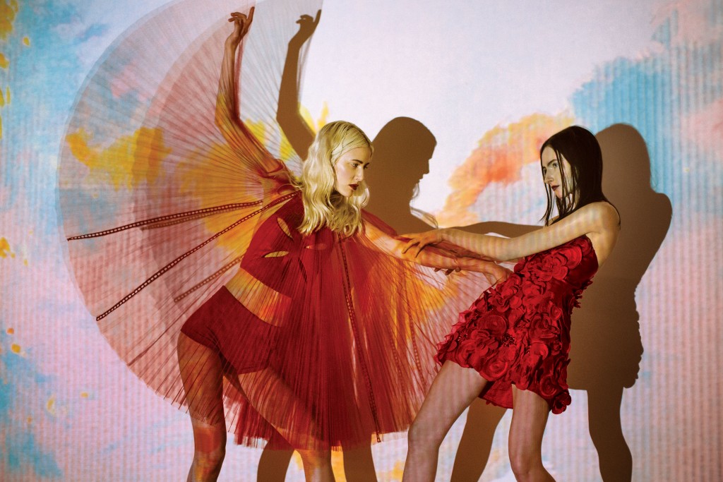 On left, Gemma Kahng leather cutout top $812, and red pleated tulle skirt $1,190; on right, Gemma Kahng flower dress $2,490, all at Tootsies. Artwork: Joey Fauerso’s single-channel video "Guadalupe — After Images," 2014, at David Shelton Gallery, Houston.