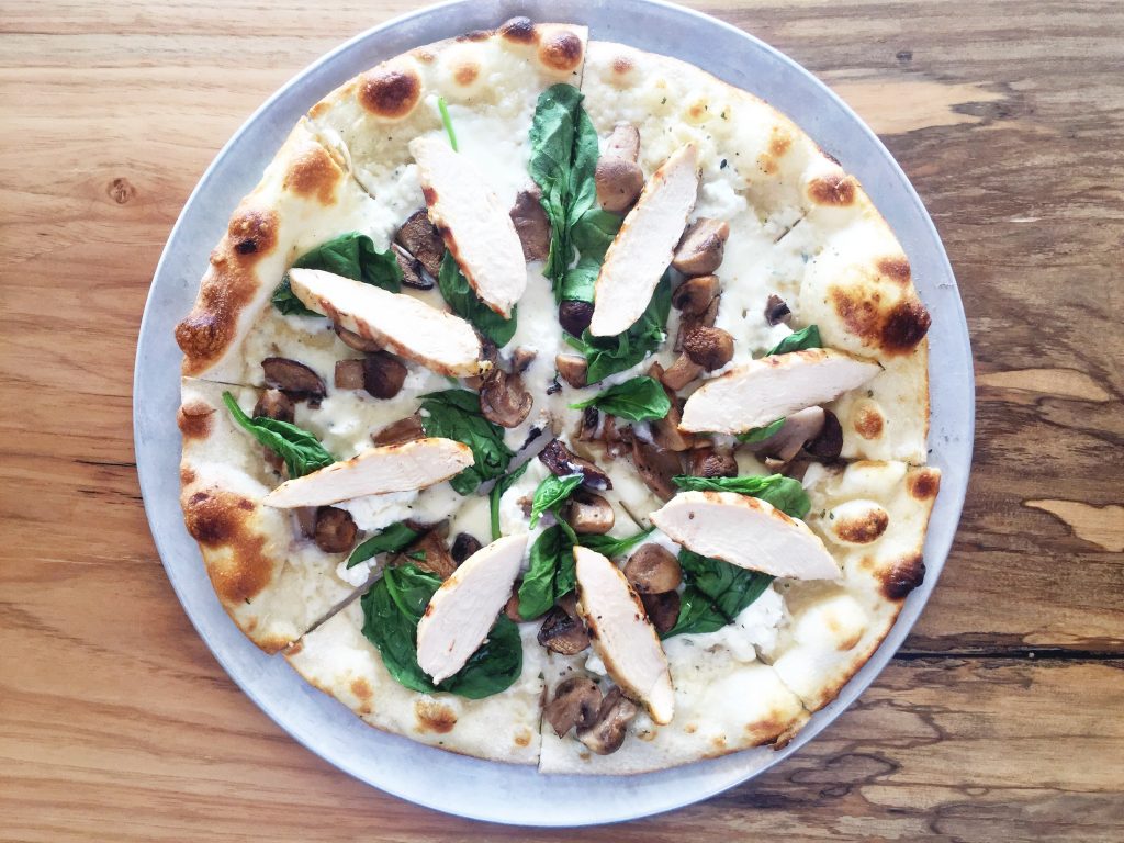 The truffle infused roasted mushroom & chicken pizza is topped with garlic white sauce, spinach and goat cheese. (Photo by Jailyn Marcel) 