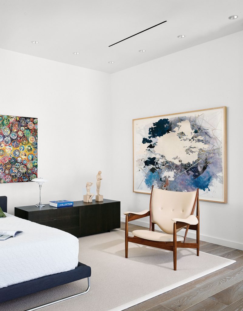 In the master bedroom, from left, Nobu Fukui’s Wonder, 2014, and Val Britton’s Unfolding Field, 2013. Minotti credenza and bed from Internum. Design Within Reach bedcovering. Vintage Finn Juhl Chieftain chair by Baker Furniture from Wright auction house in Chicago. Custom rug from Masland Carpets & Rugs. Poul Henningsen lamp from Lesco. Hand-carved wooden sculptures by Richard Senoner, Italy.