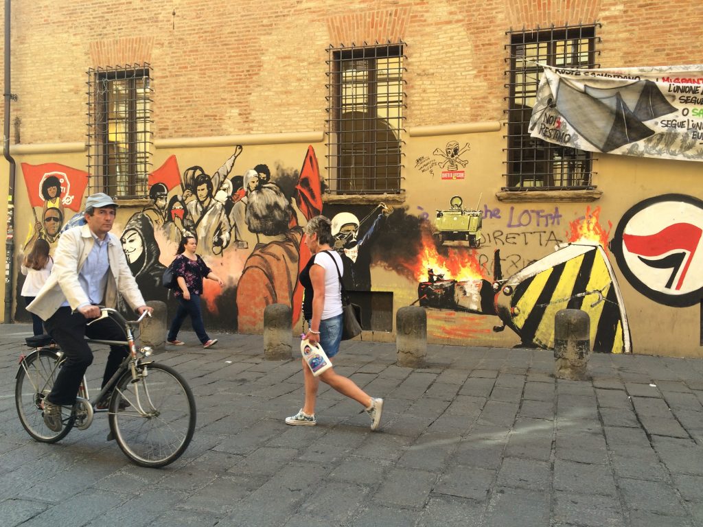 Cobblestone street near Bologna's university is lined with political street art.