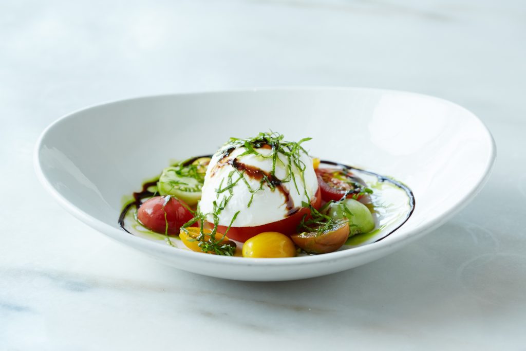 Bistro 31's burrata salad with seasonal vegetables, heirloom tomato, wild arugula, and basil-infused oil