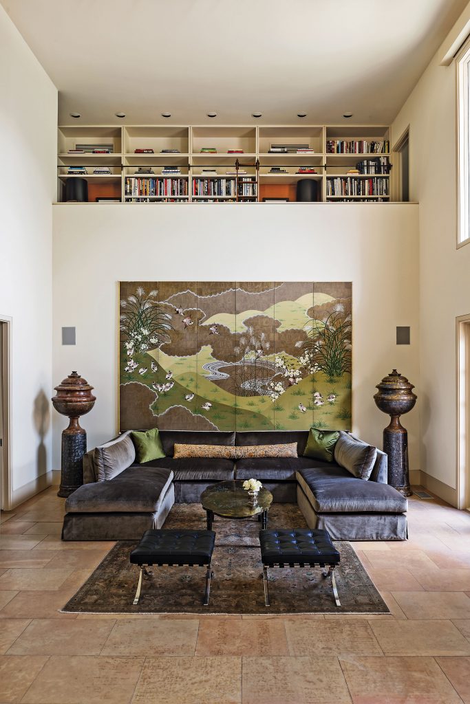 A loft above the living area serves as a library. Japanese painted screen, circa 1960, from Coconut Company, NY. Custom sofa in Donghia wool/silk velvet, with pillows in Oscar de la Renta green silk, all from Dennis Brackeen Design Group. Antique tapestry pillow from Antique Textiles Collections, NY. Philip and Kelvin LaVerne coffee table, circa 1960. Buccellati vase. Mies van der Rohe for Knoll stools. Antique Persian rug from Jamal’s Rug Collection, Los Angeles.