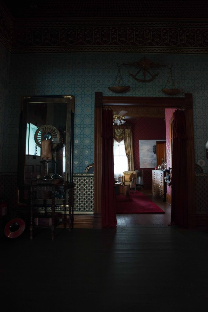 In the entry, hand-stenciled walls. David Simcik sculpture from Grange Hall. Gracie mirror was a gift from David Sutherland. Antique table from Richard Bettinger's grandmother. Italian splendor scale, 1940s, from Ceylon et Cie. In the smoking room beyond, mirrored kidney table by Karl Springer.