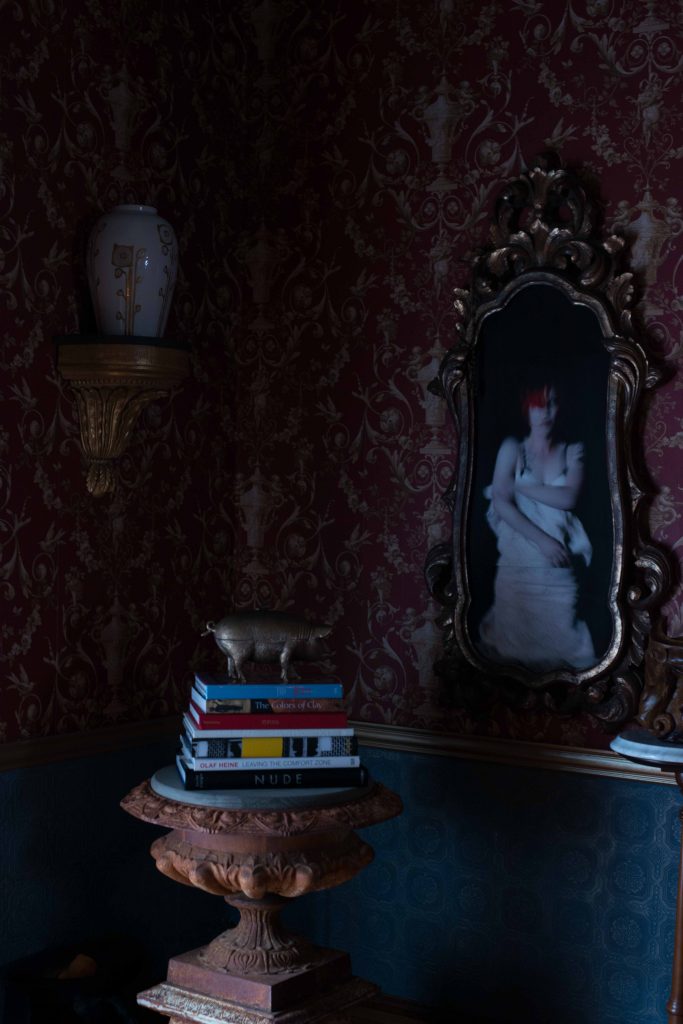 Dining-room wallpaper is a document print. Richard Bettinger's Decompressionism photograph of Lollie Bombs Burlesque dancers. Brass pig from Society. Antique Italian wall bracket, Joseph Minton Antiques. Urn is a flea-market find.