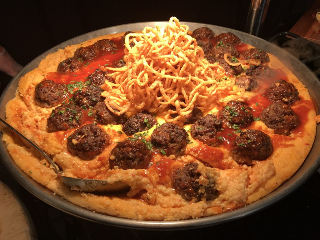 Smoked meatballs are served with pimento cheese grits. 