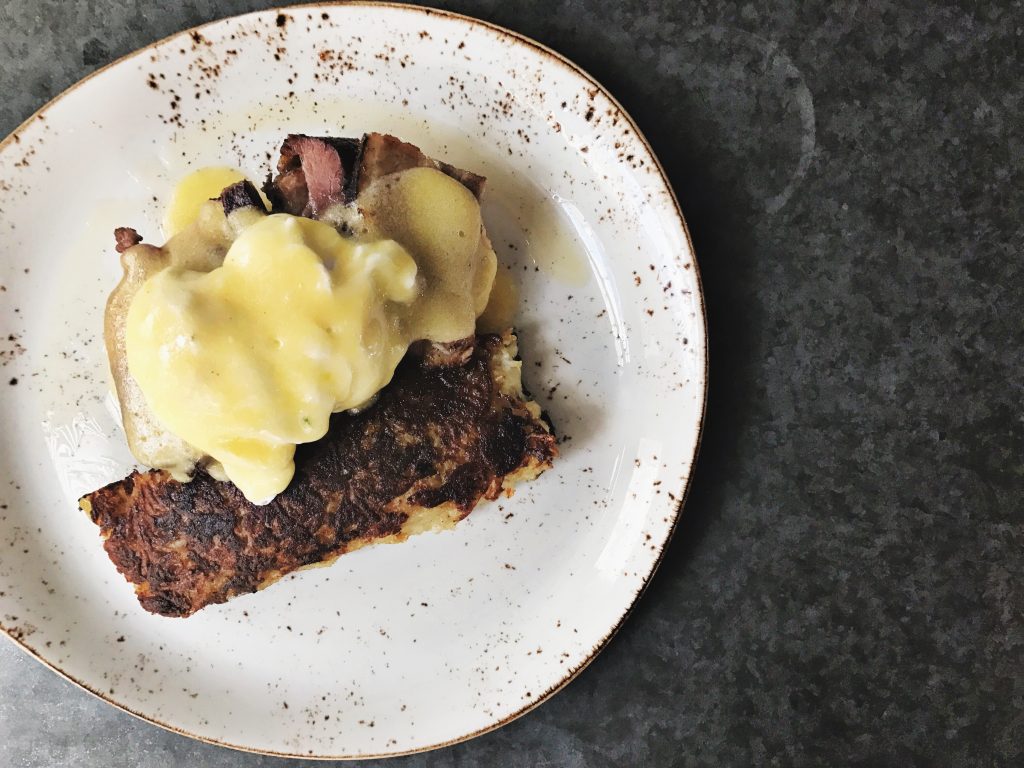 Poached eggs are served over savory pork belly at State Fare.